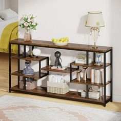 a shelf with books, vases and other items on it in a room next to a bed