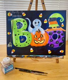 an easel with a painting on it that says boo and three pumpkins in the shape of numbers