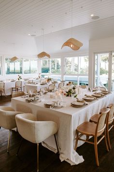 a dining room set up with white linens and place settings for people to eat