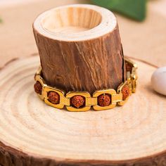 This Gold plated bracelet features a 5 face rudraksha bead, symbolizing the 5 elements, and handmade. A spiritual gift for yoga lovers, this Shiva-inspired bracelet emanates a unique and elegant energy, perfect for sophisticated tastes. Five mukhi rudraksha is a symbol of five forms of Lord Shiva, named as ‘RudraKalagni’. It helps the wearer to gain good health and peace. Rudraksha cultivates wisdom and intellect and helps to attain success in all walks of life. It brings positivity and serenity Rudraksha Bracelet, Indian Wall Decor, Rudraksha Beads, Indian Gifts, Ear Chain, 5 Elements, Singing Bowls, Bracelet For Men, Gold Plated Bracelets