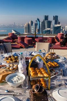 the table is set with plates, silverware and croissants on it