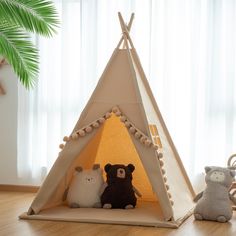 two stuffed animals sit in front of a teepee tent