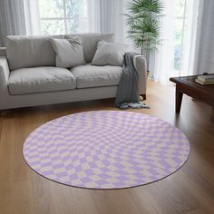 a living room with a white couch and a purple rug on the floor in front of a window