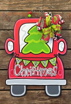 a red car with a green christmas tree on the front door is hanging from a wooden wall