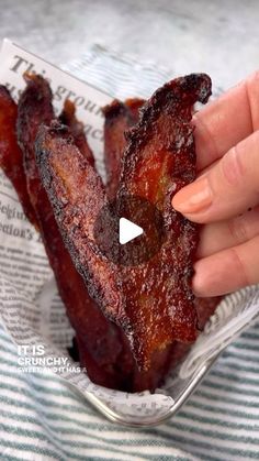 someone is holding up some bacon in a glass bowl