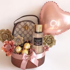 a pink heart shaped balloon sitting on top of a basket filled with chocolates and flowers