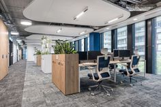 an office cubicle with chairs, desks and plants in the middle of it