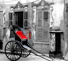 an old buggy parked in front of a building with shutters on the windows