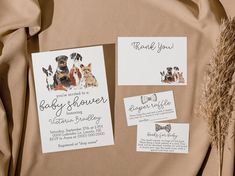 the wedding stationery is laid out on top of the fabric, with two dogs