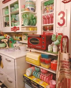 a kitchen filled with lots of different colored dishes and pans on top of shelves