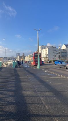 a red double decker bus driving down a street next to tall buildings