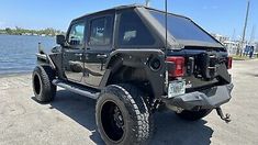 a black jeep is parked near the water