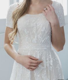 a woman in a white dress is posing for the camera with her hand on her hip