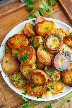 a white plate topped with potatoes and parsley on top of a gray tablecloth