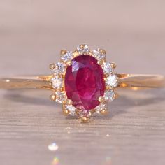 an oval shaped ruby and diamond ring on a wooden surface