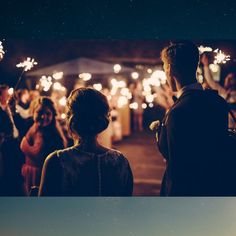 a group of people standing around each other holding sparklers in their hands and looking at them