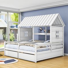 a white bed with a house on the top is in a room that has blue walls and hardwood floors