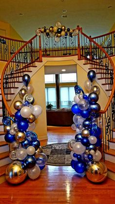 an entrance decorated with blue and silver balloons in front of a spiral stair case that leads up to the second floor