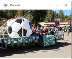 a parade float with a soccer ball on it's back and people watching from the sidelines