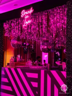 a pink and black bar with chandeliers hanging from the ceiling, in front of a neon sign that reads thank you love