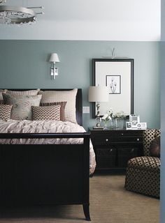 a bed room with a neatly made bed next to a chair and a mirror on the wall