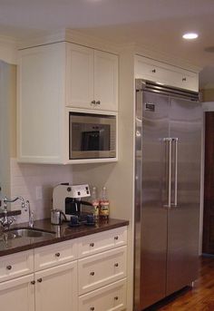 a kitchen with white cabinets and stainless steel refrigerator freezer next to a wooden floor