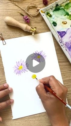 someone is painting flowers on paper with watercolors and crayon pencils