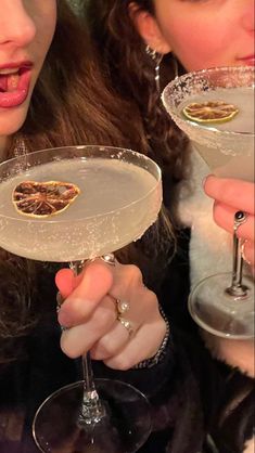 two women holding up wine glasses in front of their faces, one with a heart on it