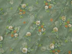 green and orange flowers are on a sheered fabric with small white dots in the center