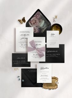 the wedding stationery is laid out in black and white with pink roses on it