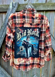 This is a one of a kind KID ROCK plaid flannel shirt.  This size XLARGE flannel shirt has two pockets on the front, buttons up and is long sleeve. On the back of the shirt is a original Kid Rock concert tee that has been sewn into the back of the flannel. The flannel has been frayed trimming around the tee. This flannel has been bleached which gives the flannel a overall distressed vintage style look.  All my shirts are ONE OF A KIND. They are all upcycled by being previously owned so there will Fall Flannel Shirt With Graphic Print, Fall Graphic Print Flannel Shirt, Plaid Flannel Shirt With Graphic Print, Plaid Graphic Print Flannel Shirt, Plaid Flannel Grunge Shirt, Plaid Flannel Shirt In Grunge Style, Grunge Plaid Flannel Shirt, Plaid Grunge Flannel Shirt, Plaid Flannel Shirt For Fall, Grunge Style