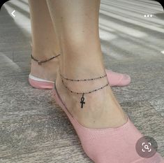 a woman's foot with a small cross tattoo on her left ankle, while wearing pink slippers