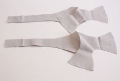 two pieces of white paper are cut out to look like bow ties on a table