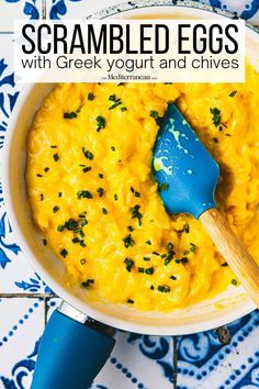 scrambled eggs with greek yogurt and chives in a bowl on a blue and white tile background