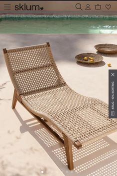 a wooden lounge chair sitting on top of a sandy beach