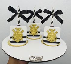 three cakes decorated with gold and black ribbons on top of a white cake platter