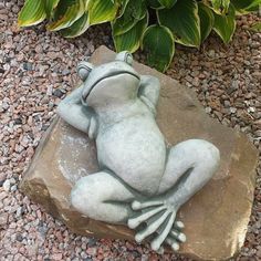 a frog statue sitting on top of a rock