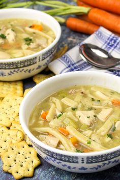 two bowls of chicken noodle soup with crackers and carrots on the side