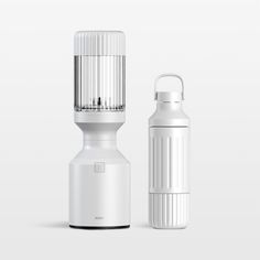 a white bottle next to a white and black blender on a gray background with the lid off