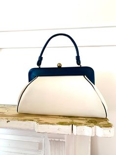 "Vintage vinyl spectator handbag. Extra large size. Little wear( photos show marks), clean interior, no Oder, strong clasp and handle.  The lean of the bag is an intentional design; not mis-shapen. The back is meant to lay flatter against the body. Pretty smart actually.  Measurements are approximate  Height 8\" not including clasp  Width 14\" Depth 4\" Strap drop 6\"" Retro Blue Bags For Formal Occasions, Retro Blue Evening Bags, Blue Retro Evening Bag, Vintage Blue Top Handle Bag, White Retro Satchel With Detachable Strap, Vintage Blue Satchel With Removable Pouch, Retro Blue Top Handle Shoulder Bag, Retro Satchel With Detachable Handle In Clutch Shape, Retro Satchel With Detachable Handle Clutch