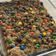 a cookie bar with m & m cookies and candy bars on top in a glass baking dish