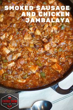 a skillet filled with cooked sausage and chicken jambajaa next to spoons