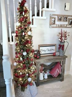 a christmas tree decorated with red, white and silver ornaments next to a wooden bench