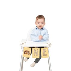 a baby sitting in a high chair with one sign on it's legs and holding a teddy bear