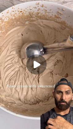 a man standing in front of a mixing bowl filled with chocolate frosting and holding a spoon