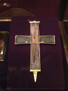 a wooden cross on display in a case with purple velvet and gold trimmings