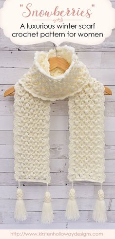 a white knitted scarf with tassels hanging on a wooden hanger and text overlay that says snowberries luxurious winter scarf crochet pattern for women