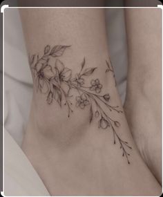 a woman's foot with flowers and leaves tattooed on the bottom of her leg