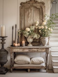 an old table with flowers and candles on it in front of a wooden paneled wall