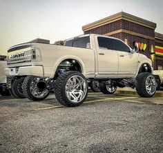 a white ram truck parked in front of a building with chrome rims and tires